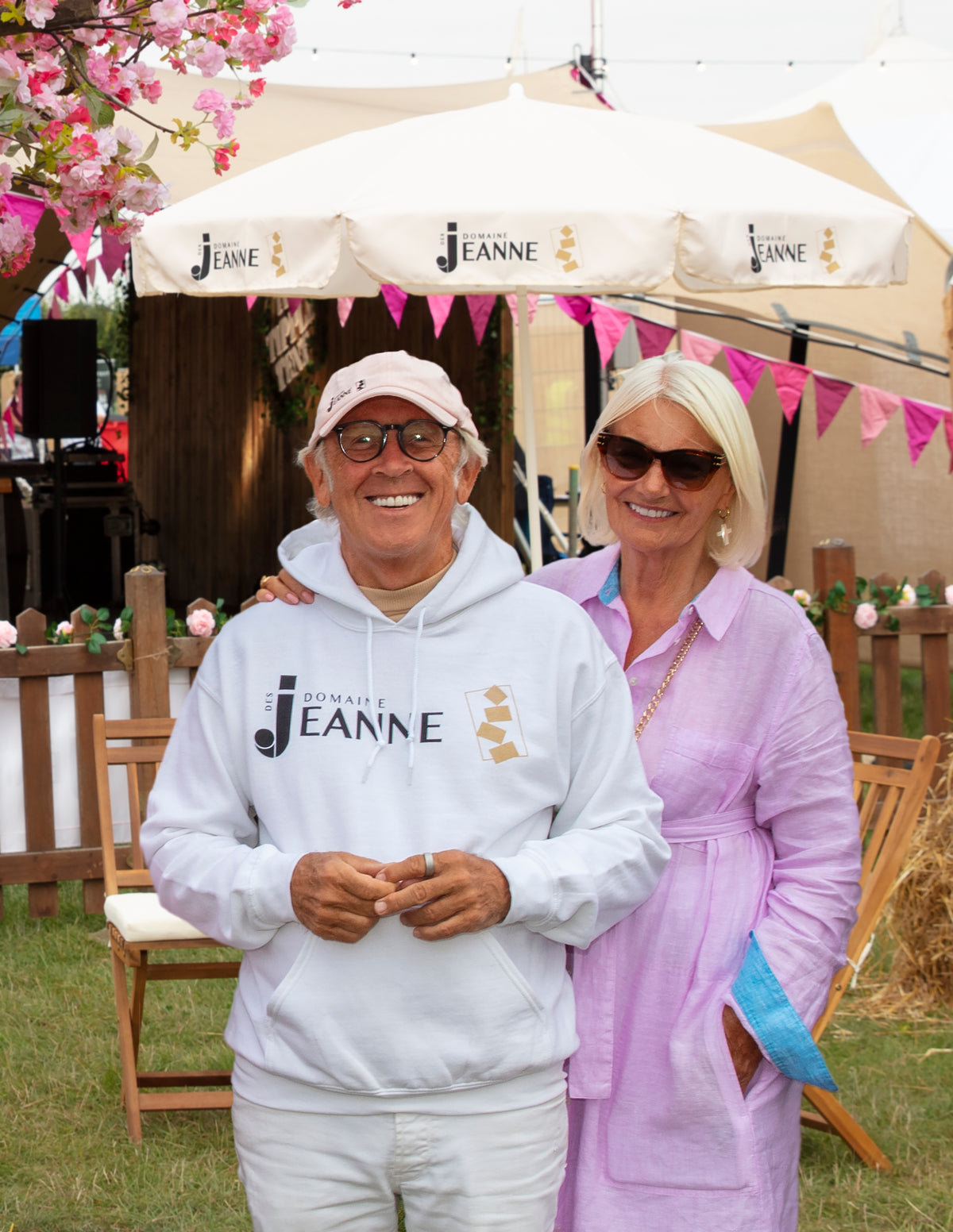 White Domaine des Jeanne hoodie with black and gold logo under the parasols at CarFest