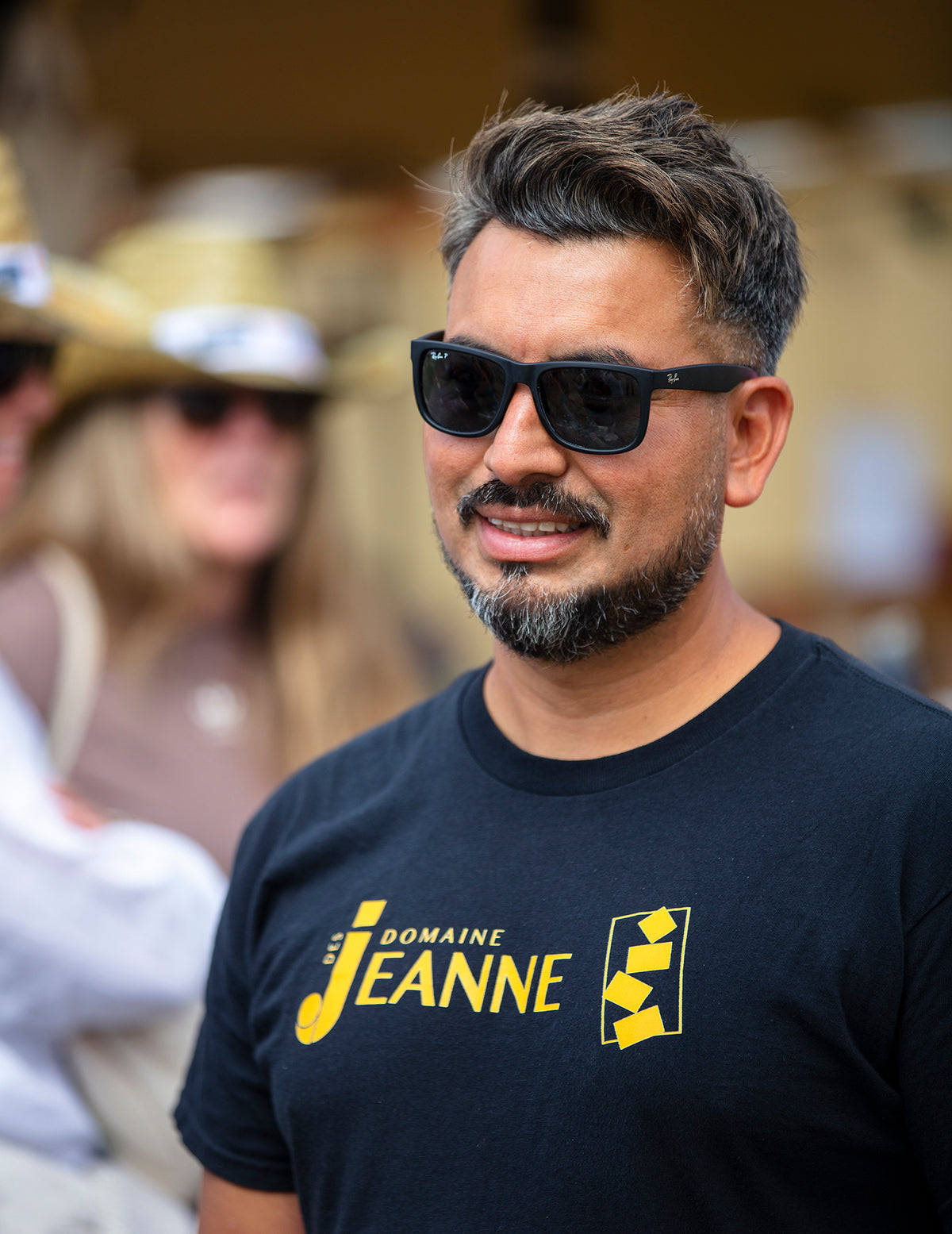 Black Domaine des Jeanne t-shirt with gold logo, worn at a summer festival