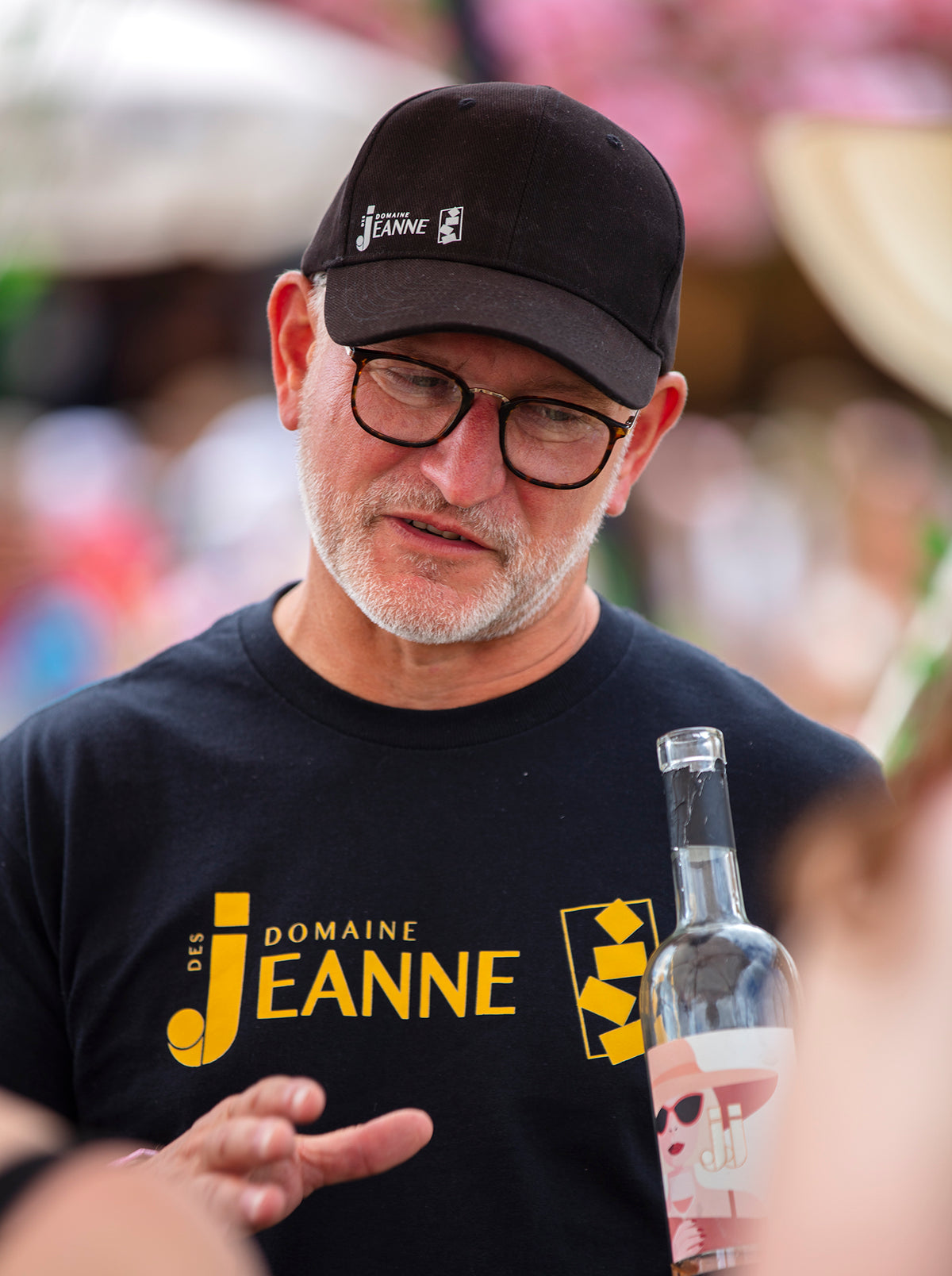 Black Domaine des Jeanne cap and t-shirt with gold logo at a festival