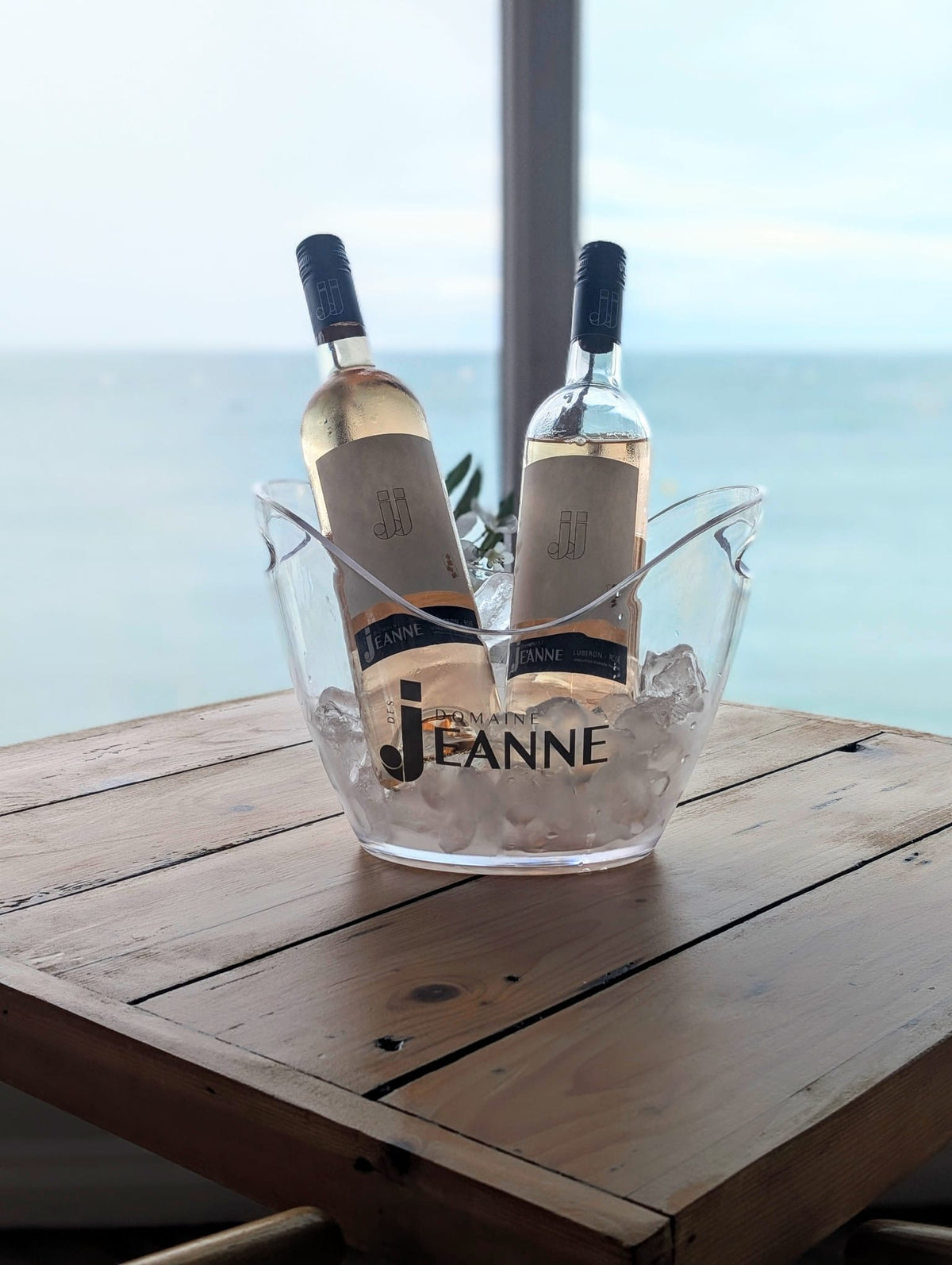 Two bottles of JJ Rosé in a Domaine des Jeanne ice bucket by the sea in Abersoch